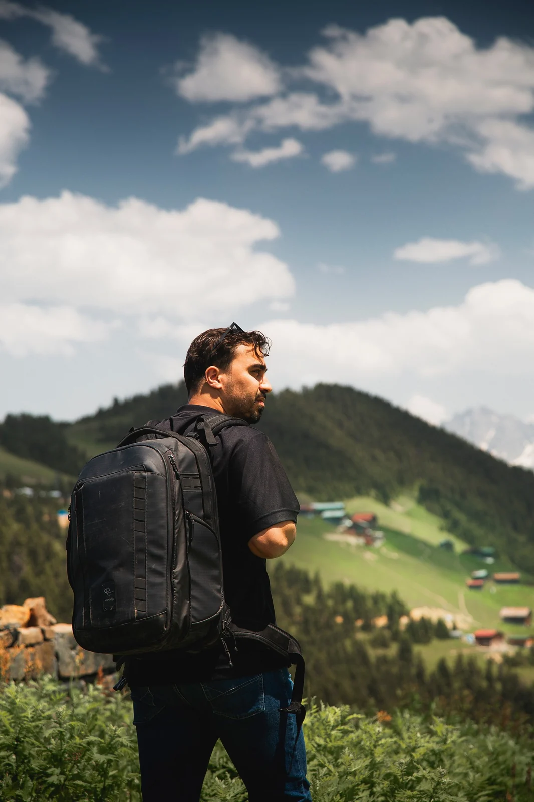 Toghrul Hasanbeyli with his camera backpack, looking over a mountain village