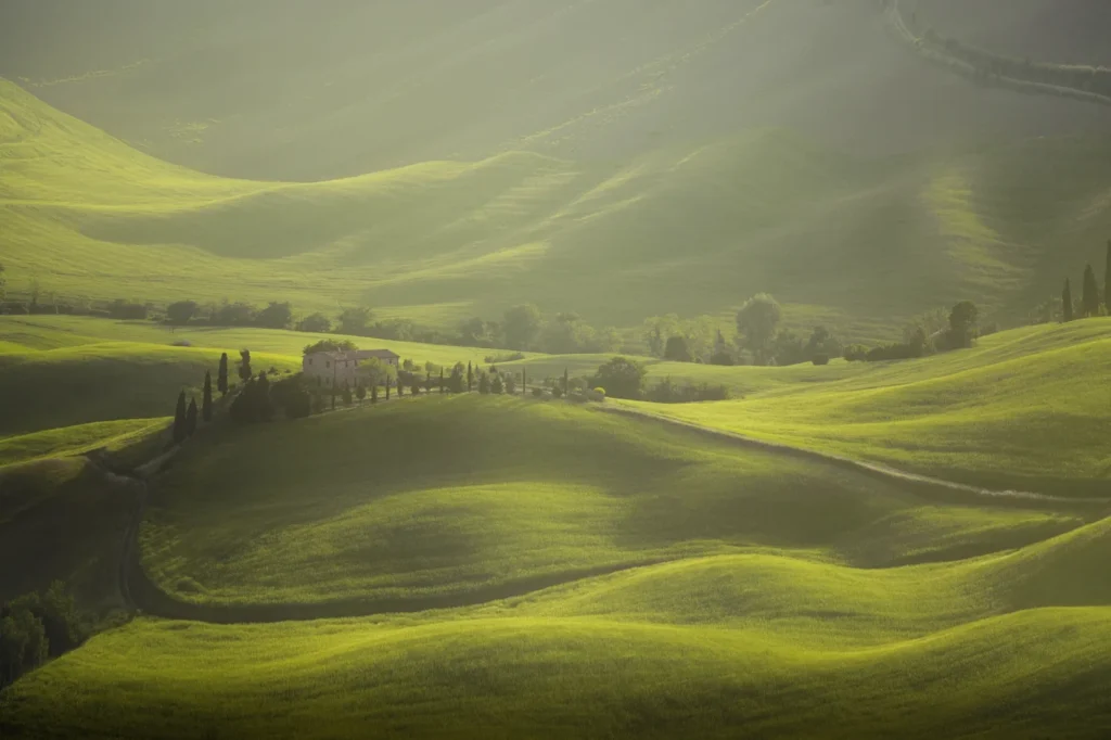 A stone farmhouse with cypresses among rolling green hills, Val d'Orcia, Tuscany