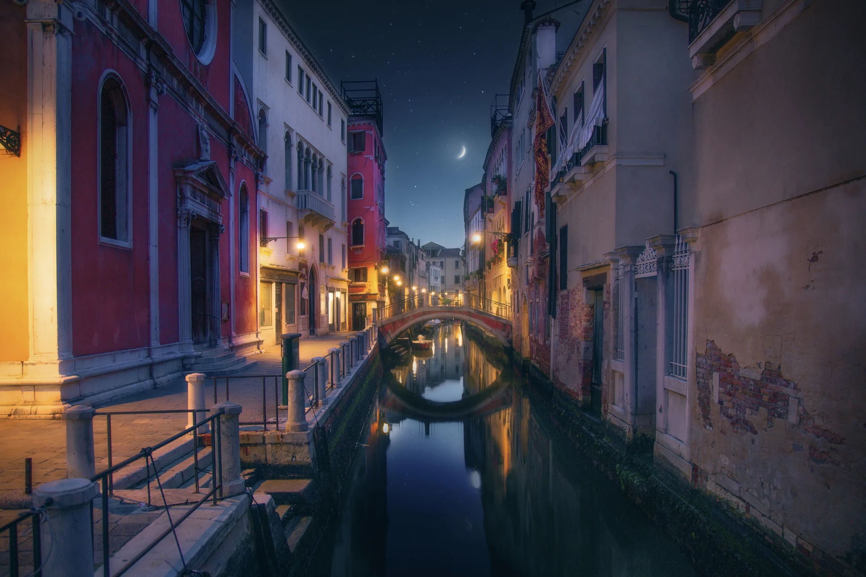 A quiet Venice canal at night under a crescent moon